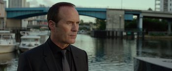 Movie still from “Ride Along 2” (2016), directed by Tim Story – A man wearing a suit and tie standing next to a body of water; Close Up shot, Over the shoulder angle