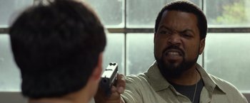 Movie still from “Ride Along 2” (2016), directed by Tim Story – A man holding a gun in front of another man; Close Up shot, Over the shoulder angle