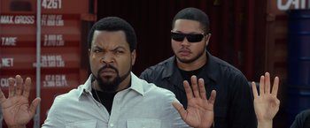 Movie still from “Ride Along 2” (2016), directed by Tim Story – Two men standing next to each other in front of a building; Close Up shot, Over the shoulder angle