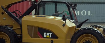 Movie still from “Ride Along 2” (2016), directed by Tim Story – The cat logo on the cab of a yellow tractor; Medium shot, High angle