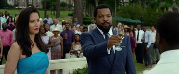 Movie still from “Ride Along 2” (2016), directed by Tim Story – A man holding a wine glass in front of a crowd; Medium shot, Over the shoulder angle