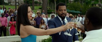 Movie still from “Ride Along 2” (2016), directed by Tim Story – A woman and a man are holding wine glasses; Medium shot, Over the shoulder angle