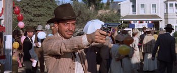 Movie still from “Ride the High Country” (1962), directed by Sam Peckinpah – A man with a hat on holding a gun in front of a group of people; Close Up shot, Low angle