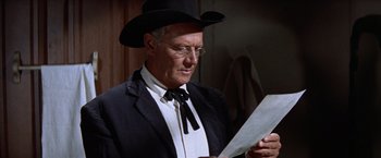 Movie still from “Ride the High Country” (1962), directed by Sam Peckinpah – An older man wearing a suit and a cowboy hat while reading a paper; Close Up shot, Low angle
