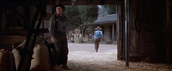 Movie still from “Ride the High Country” (1962), directed by Sam Peckinpah – A man and a woman walking through a dirt field; Wide shot, Low angle