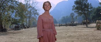 Movie still from “Ride the High Country” (1962), directed by Sam Peckinpah – A woman in a pink dress standing on a dirt field; Medium shot, Low angle