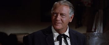 Movie still from “Ride the High Country” (1962), directed by Sam Peckinpah – An older man wearing a suit and a tie; Close Up shot, Over the shoulder angle