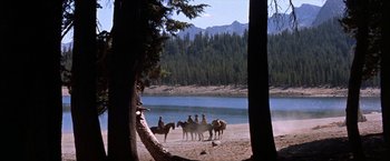 Movie still from “Ride the High Country” (1962), directed by Sam Peckinpah – A group of people riding horses near a body of water; Extreme Wide shot, High angle