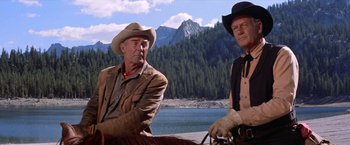 Movie still from “Ride the High Country” (1962), directed by Sam Peckinpah – Two men sitting next to each other near a body of water; Medium shot, Low angle