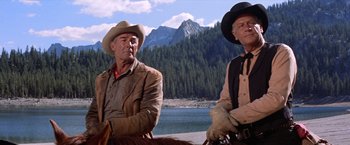 Movie still from “Ride the High Country” (1962), directed by Sam Peckinpah – Two men sitting next to each other in front of a body of water; Medium shot, Low angle