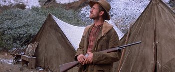 Movie still from “Ride the High Country” (1962), directed by Sam Peckinpah – A man holding a rifle while standing in front of a tent; Medium shot, Low angle
