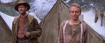 Movie still from “Ride the High Country” (1962), directed by Sam Peckinpah – A man standing next to another man in front of a tent; Medium shot, Low angle