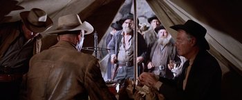 Movie still from “Ride the High Country” (1962), directed by Sam Peckinpah – A group of men standing next to each other in a tent; Medium shot, Over the shoulder angle
