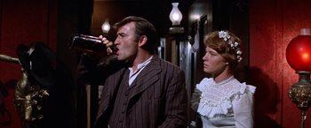 Movie still from “Ride the High Country” (1962), directed by Sam Peckinpah – A man and a woman are drinking from a bottle; Medium shot, Low angle