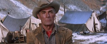 Movie still from “Ride the High Country” (1962), directed by Sam Peckinpah – An older man wearing a cowboy hat and a brown jacket; Close Up shot, Over the shoulder angle