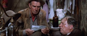 Movie still from “Ride the High Country” (1962), directed by Sam Peckinpah – A man sitting on the ground holding a piece of paper; Close Up shot, Over the shoulder angle
