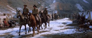 Movie still from “Ride the High Country” (1962), directed by Sam Peckinpah – A group of men riding horses down a snow covered road; Wide shot, Low angle