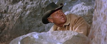 Movie still from “Ride the High Country” (1962), directed by Sam Peckinpah – A man wearing a cowboy hat in front of a rock wall; Close Up shot, Low angle