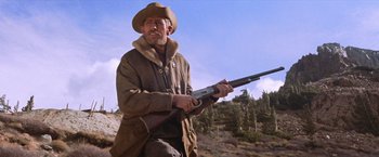 Movie still from “Ride the High Country” (1962), directed by Sam Peckinpah – A man holding a rifle while standing on top of a hill; Medium shot, Low angle