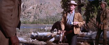 Movie still from “Ride the High Country” (1962), directed by Sam Peckinpah – A man in a cowboy hat holding a gun and standing next to a black bear; Medium shot, Low angle