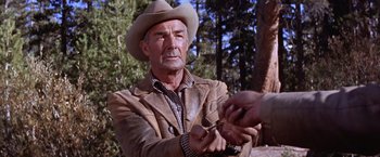 Movie still from “Ride the High Country” (1962), directed by Sam Peckinpah – An older man wearing a cowboy hat holding a pair of shears; Close Up shot, Over the shoulder angle