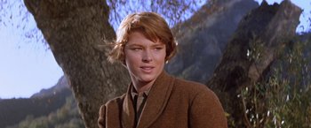 Movie still from “Ride the High Country” (1962), directed by Sam Peckinpah – A woman in a brown coat standing in front of a tree; Close Up shot, Low angle