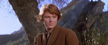 Movie still from “Ride the High Country” (1962), directed by Sam Peckinpah – A woman in a brown coat standing in front of a tree; Close Up shot, Low angle