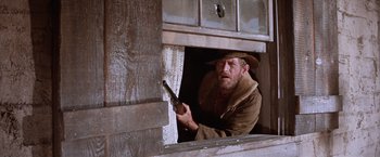 Movie still from “Ride the High Country” (1962), directed by Sam Peckinpah – A man holding a gun looking out of a window; Medium shot, Low angle