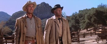 Movie still from “Ride the High Country” (1962), directed by Sam Peckinpah – Two men in cowboy hats and jackets standing next to each other; Medium shot, Low angle