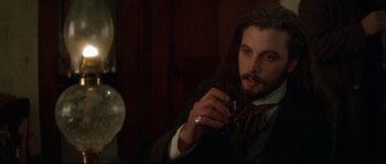 Movie still from “Ride with the Devil” (1999), directed by Ang Lee – A man with long black hair is holding a wine glass; Close Up shot, High angle
