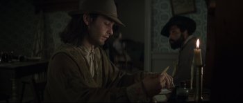 Movie still from “Ride with the Devil” (1999), directed by Ang Lee – A man wearing a hat is writing on a piece of paper; Medium shot, Over the shoulder angle