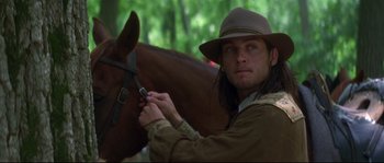 Movie still from “Ride with the Devil” (1999), directed by Ang Lee – A man wearing a hat is grooming a horse; Close Up shot, Over the shoulder angle