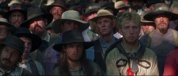 Movie still from “Ride with the Devil” (1999), directed by Ang Lee – A group of men in cowboy hats standing in a crowd; Medium shot, Low angle