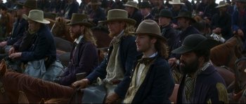 Movie still from “Ride with the Devil” (1999), directed by Ang Lee – A group of men sitting next to each other wearing hats; Medium shot, Over the shoulder angle