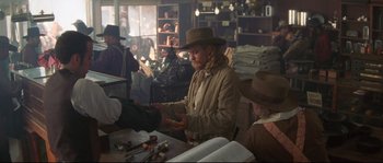 Movie still from “Ride with the Devil” (1999), directed by Ang Lee – A man wearing a cowboy hat is holding something in his hand; Medium shot, Over the shoulder angle