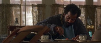 Movie still from “Ride with the Devil” (1999), directed by Ang Lee – A bearded man cutting a piece of cake with a knife and fork; Medium shot, Low angle