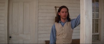 A man with long brown hair wearing a vest