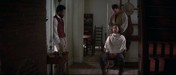 Movie still from “Ride with the Devil” (1999), directed by Ang Lee – A man getting his hair cut by two men; Medium shot, Over the shoulder angle