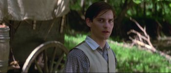 Movie still from “Ride with the Devil” (1999), directed by Ang Lee – A young man in a vest standing next to a tree; Close Up shot, Over the shoulder angle