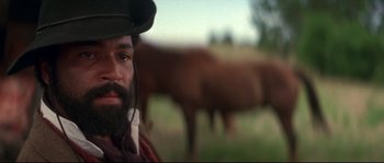 Movie still from “Ride with the Devil” (1999), directed by Ang Lee – A man with a beard and a cowboy hat in front of a herd of cattle; Close Up shot, Low angle