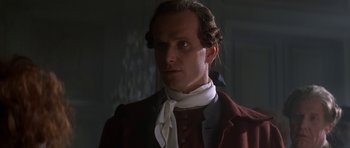 Movie still from “Ridicule” (1996), directed by Patrice Leconte – A person wearing a suit and tie; Close Up shot, Over the shoulder angle