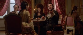 Movie still from “Ridicule” (1996), directed by Patrice Leconte – A group of people sitting around a table; Medium shot, Over the shoulder angle