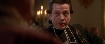 Movie still from “Ridicule” (1996), directed by Patrice Leconte – A person wearing a suit and tie; Close Up shot, Over the shoulder angle