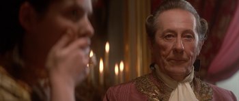 Movie still from “Ridicule” (1996), directed by Patrice Leconte – A man in a red and gold jacket smoking a cigarette; Close Up shot, Over the shoulder angle