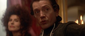 Movie still from “Ridicule” (1996), directed by Patrice Leconte – A person wearing a black jacket; Close Up shot, Over the shoulder angle