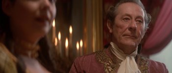 Movie still from “Ridicule” (1996), directed by Patrice Leconte – An older man wearing a red and gold jacket; Close Up shot, Over the shoulder angle