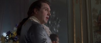 Movie still from “Ridicule” (1996), directed by Patrice Leconte – A man in a blue jacket and a white shirt; Close Up shot, Over the shoulder angle