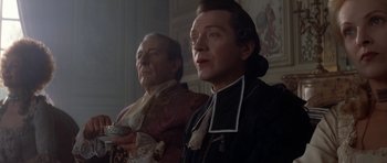Movie still from “Ridicule” (1996), directed by Patrice Leconte – A man in a priest's outfit stands next to another man; Medium shot, Low angle