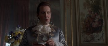Movie still from “Ridicule” (1996), directed by Patrice Leconte – A man in a blue and white outfit holding a knife; Medium shot, Low angle