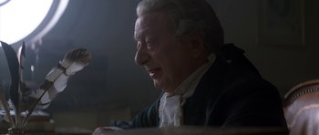 Movie still from “Ridicule” (1996), directed by Patrice Leconte – An older man with a white beard and a white shirt; Close Up shot, Over the shoulder angle